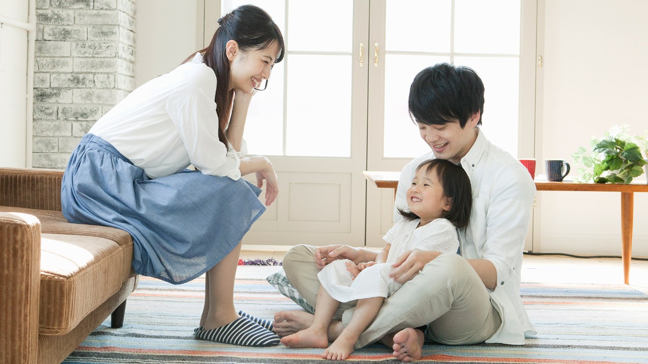 Daughter sitting on father's lap in living room; image used for HSBC Macau Insurance page