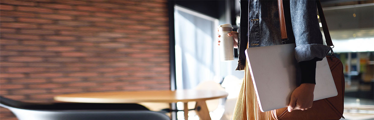 A woman holding a laptop and a flask in a coffee shop; image used for HSBC MO security centre page