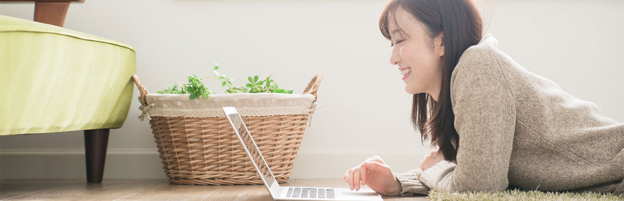 A woman lying on the floor using laptop happily; image used for HSBC MO fraud guide page